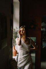talented sculptor girl in light negligee stands in pottery workshop near large window. concept is beauty and art.
