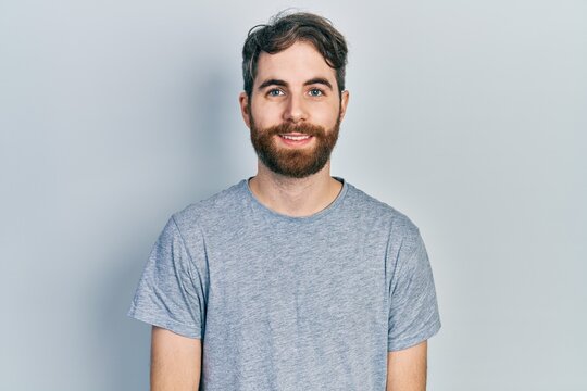 Caucasian man with beard wearing casual grey t shirt with a happy and cool smile on face. lucky person.