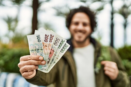 Handsome hispanic man holding czech crown banknotes at the city