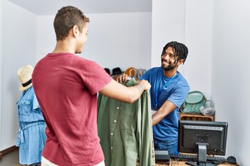 Two men shopkeeper and customer choosing shirt at clothing store