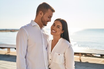 Obraz premium Man and woman couple smiling happy hugging each other standing at seaside