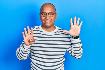 Naklejka premium Middle age latin man wearing casual clothes and glasses showing and pointing up with fingers number nine while smiling confident and happy.
