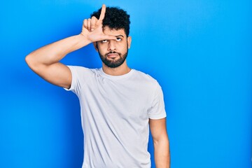 Young arab man with beard wearing casual white t shirt making fun of people with fingers on...