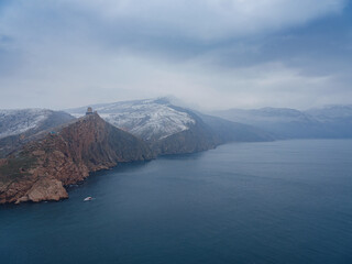 ancient castle ruins on a beautiful rock rise above the sea. winter season, snow is falling.