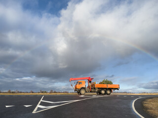Fototapeta premium Rainbow over straight road with truck.