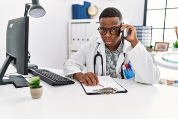 Young african man working as doctor speaking on the phone at medical clinic