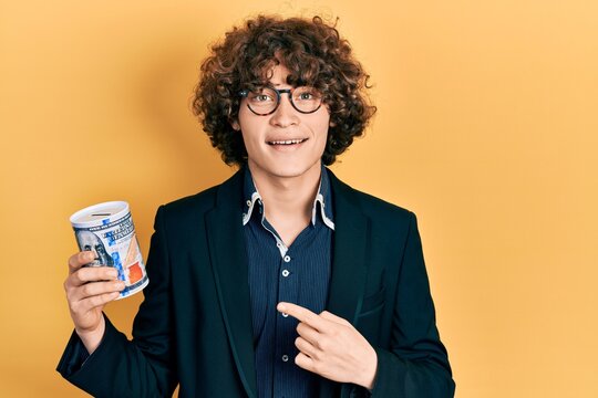 Handsome young man holding piggy bank smiling happy pointing with hand and finger