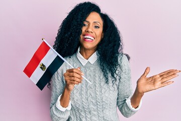 Middle age african american woman holding egypt flag celebrating achievement with happy smile and winner expression with raised hand