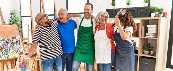 Group of middle age draw students smiling happy and hugging at art studio.