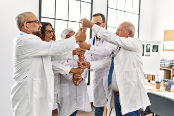 Obraz premium Group of middle age doctor smiling happy bulding tower with fists in a medical meeting at the clinic office.