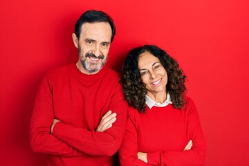 Middle age couple of hispanic woman and man hugging and standing together happy face smiling with crossed arms looking at the camera. positive person.