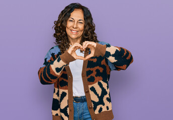 Middle age hispanic woman wearing casual clothes smiling in love doing heart symbol shape with hands. romantic concept.