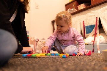 Fototapeta premium Mädchen im Kindergartenalter spielt mit Mutter im Kinderzimmer
