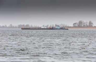 A cargo barge together with a pusher boat go along the Kama River. A barge built by the USSR, the...
