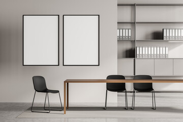 Two canvases on wall of beige meeting room with shelving on background
