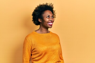 Fototapeta na wymiar Young african american woman wearing casual clothes looking away to side with smile on face, natural expression. laughing confident.