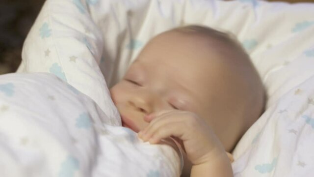 Baby wrapped in a blanket falls asleep, six month old infant face closeup. High quality 4k footage