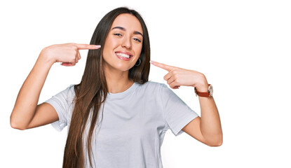 Fototapeta premium Young hispanic girl wearing casual white t shirt smiling cheerful showing and pointing with fingers teeth and mouth. dental health concept.