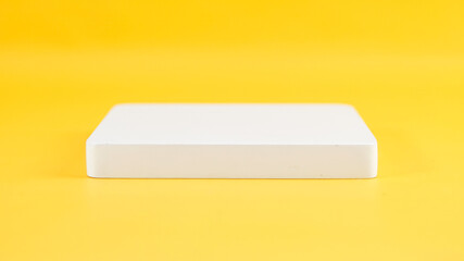 blank white product podium on yellow background