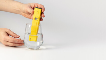 Banner. Hand with a pH meter on a white background. Measuring the characteristics of drinking...