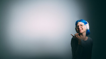 Music lover. DJ accessory. Audio technology. Happy smiling woman in headphones isolated on light spotlight dark copy space background.