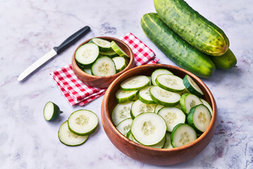  Bowl of slices of cucumber on a marble surface