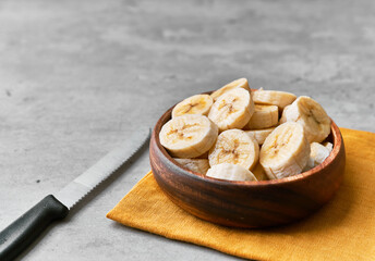Photo of banana slices in a bowl on a concrete surface