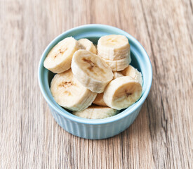  Bowl of slices of banana on a wooden table