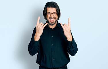 Fototapeta premium Middle age caucasian man wearing casual clothes and glasses shouting with crazy expression doing rock symbol with hands up. music star. heavy concept.