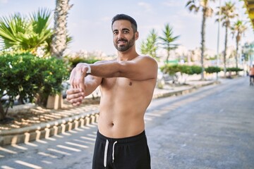 Hispanic man stretching after working out outdoors on a sunny day