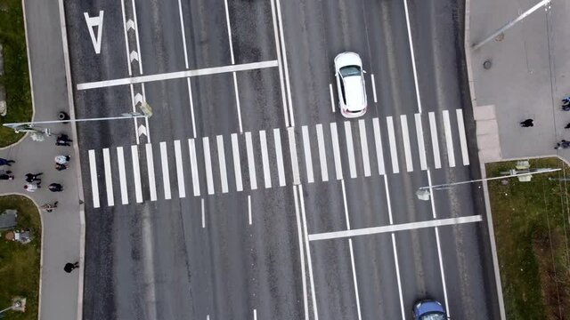 Aerial video filming. People walk along the pedestrian crossing. Cars pass along the road. View from above.