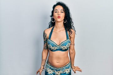 Fototapeta premium Young woman wearing bindi and traditional belly dance clothes looking at the camera blowing a kiss on air being lovely and sexy. love expression.