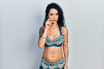 Fototapeta premium Young woman wearing bindi and traditional belly dance clothes mouth and lips shut as zip with fingers. secret and silent, taboo talking