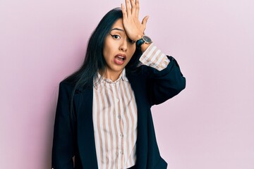 Young hispanic girl wearing business clothes surprised with hand on head for mistake, remember...
