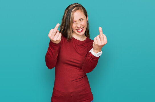 Young blonde woman wearing casual clothes showing middle finger doing fuck you bad expression, provocation and rude attitude. screaming excited