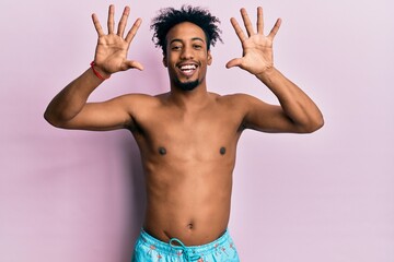 Young african american man with beard wearing swimsuit showing and pointing up with fingers number ten while smiling confident and happy.