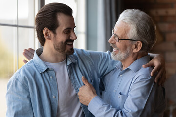 True friends. Excited elderly dad embrace adult son glad to hear good news congratulate with...
