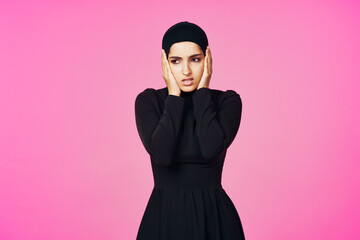 cheerful muslim woman in black hijab posing fashion pink background