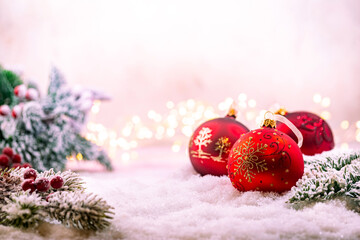 Christmas red decorations on snow with fir tree branches and christmas lights. Winter Decoration Background