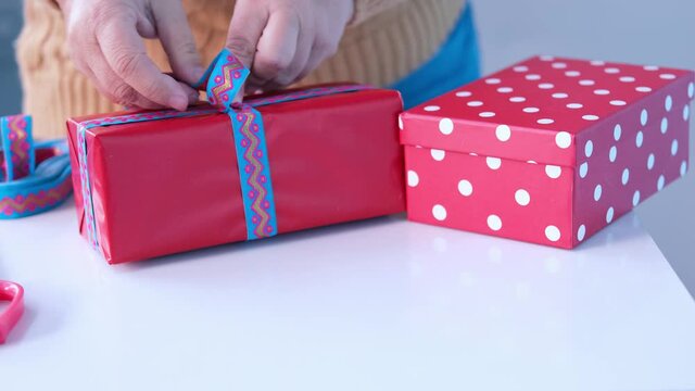 close-up female hands packing gifts in two red boxes, giving gifts to loved ones for the holiday, concept of a festive mood, christmas, mother's day, birthday, valentine's day