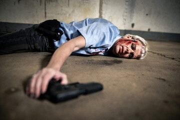 Person liegt nach Kopfschuss mit Pistole in der Hand blutig auf dem dreckigen Boden