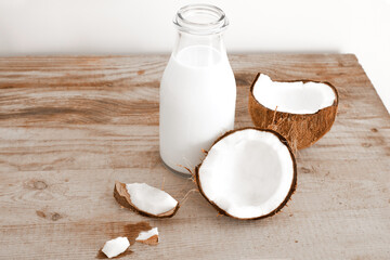 Fototapeta na wymiar Fresh coconut milk in glass bottle, vegan non dairy healthy drink. Wooden table, close-up.