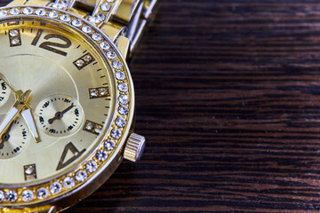 Women's wrist watch of gold color on a dark background.