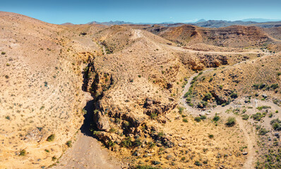 Aerial view of dry canyon in the desert terrain with red rocks in a natural national park. Hiking and recreation area