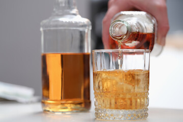 Hand pours alcohol from a bottle into a glass