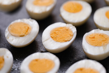 Boiled chicken eggs cut in half on dark background