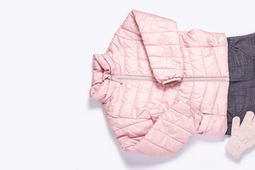 Jacket, gloves and pants for a child girl on a white background. Top view, flat lay.