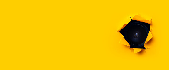 Yellow torn paper cardboard inside a hole in the camera. Banner.