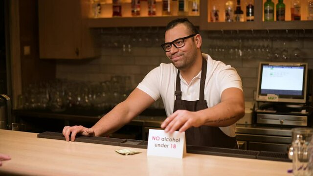 The bartender refuses a drink to a young man who is under eighteen years old. Illustration of compliance with the law on the sale of alcohol to minors