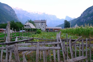 Fototapeta na wymiar Scenery of famous mountain village Theth in Theth Valley with wooden fence, on background the mountains of Albanian Alps